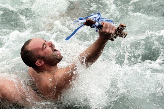 A man has just retrieved the cross and holds it with pride. Photo by Sakis Mitrolidis